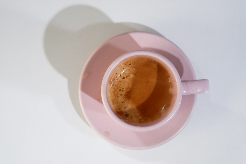Top-down view of pale pink coffee cup holding coffe with a beautiful crema